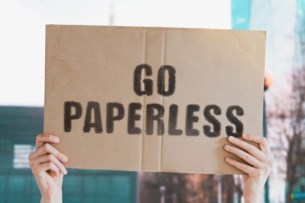 Hands holding sign saying Go Paperless